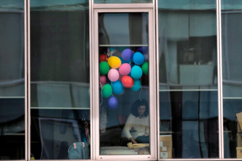 A woman sits at a desk as balloons decorate a cubicle in an office building in Bucharest, Romania, Friday, Dec. 14, 2018. Vadim Ghirda/AP Photo.