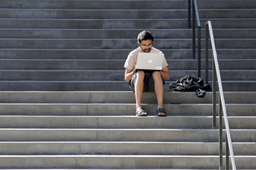 Amazon software engineer Aditya Iyer sits alone on steps outside the company headquarters, and across the street from his apartment building, as he works on his laptop Friday, March 20, 2020. Elaine Thompson/AP Photo.