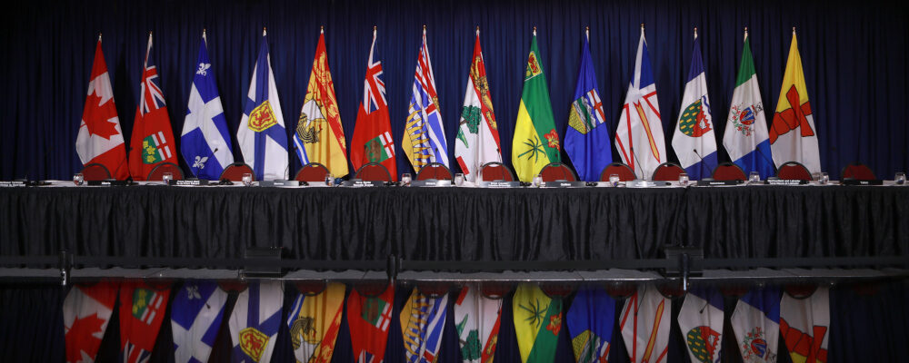 The flags of provinces and territories are displayed before a question period with premiers on the final day of the summer meeting of the Canada's Premiers at the Fairmont Empress in Victoria, B.C., on Tuesday, July 12, 2022 Chad Hipolito/The Canadian Press.