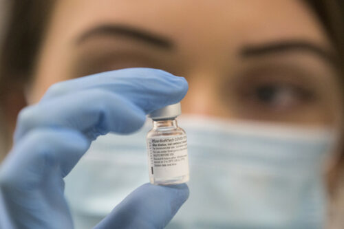 A worker holds a bottle of the Pfizer-BioNTech COVID-19 vaccine as the mass public vaccination program gets underway in the United Kingdom on Dec. 8, 2020. Graeme Robertson/AP Photo.