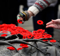 People place poppies on the Tomb of the Unknown Soldier at the National War Memorial following the National Remembrance Day Ceremony in Ottawa, on Thursday, Nov. 11, 2021. Justin Tang/The Canadian Press.