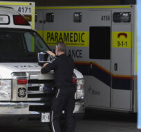 A paramedic works on a laptop on the hood of their ambulance, outside the Emergency Department at the Ottawa Hospital Civic Campus in Ottawa on May 16, 2022. Justin Tang/The Canadian Press.