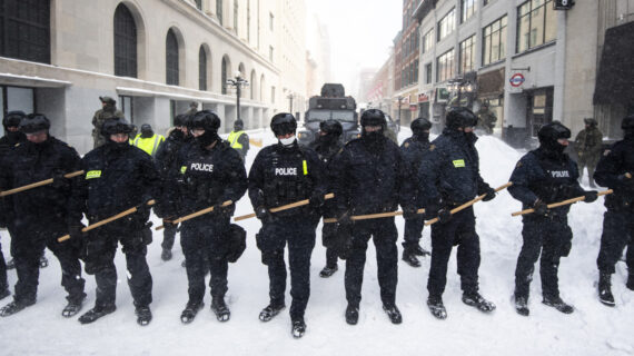 Police clutch batons as they take action to put an end to a protest, which started in opposition to mandatory COVID-19 vaccine mandates and grew into a broader anti-government demonstration and occupation in Ottawa on Feb. 19, 2022. Justin Tang/The Canadian Press.