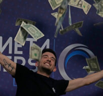 A man throws fake dollar banknotes at a cryptocurrency event in Madrid, Spain, Saturday Aug. 27, 2022. Paul White/AP Photo.