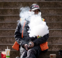 A construction worker exhales after using a vaping device while eating lunch on the steps at Robson Square, in Vancouver, on Monday, March 8, 2021. Darryl Dyck/The Canadian Press.