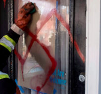 A graffiti removal worker cleans anti-Semitic graffiti, including a swastika, that was spray painted on the door of The Glebe Minyan and home of Rabbi Anna Maranta, on Tuesday, Nov. 15, 2016 in Ottawa. Justin Tang/The Canadian Press. 