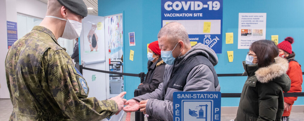 A member of the Canadian Armed Forces dispenses hand sanitizer at a COVID-19 vaccination site in Montreal, Sunday, January 16, 2022. Graham Hughes/The Canadian Press. 