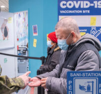 A member of the Canadian Armed Forces dispenses hand sanitizer at a COVID-19 vaccination site in Montreal, Sunday, January 16, 2022. Graham Hughes/The Canadian Press. 