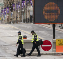 Parliamentary security personnel walk past a barrier indicating a road closure on Wellington St. in front of Parliament Hill on April 27, 2022 in Ottawa.  Adrian Wyld/The Canadian Press.