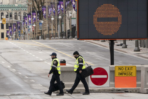 Parliamentary security personnel walk past a barrier indicating a road closure on Wellington St. in front of Parliament Hill on April 27, 2022 in Ottawa.  Adrian Wyld/The Canadian Press.