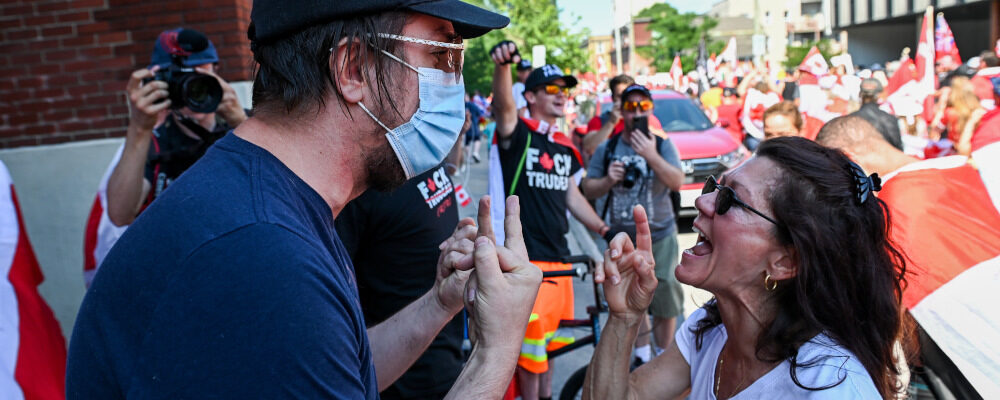 A person protesting against COVID-19 health measures, right, argues with a counter-protestor during a demonstration in the downtown core of Ottawa, Ont. during Canada Day celebrations on Friday, July 1, 2022. Spencer Colby/The Canadian Press. 
