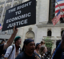 In this July 11, 2012 file photo, Occupy Wall Street protestors walk past the New York Stock Exchange in New York. Frank Franklin II/AP Photo.