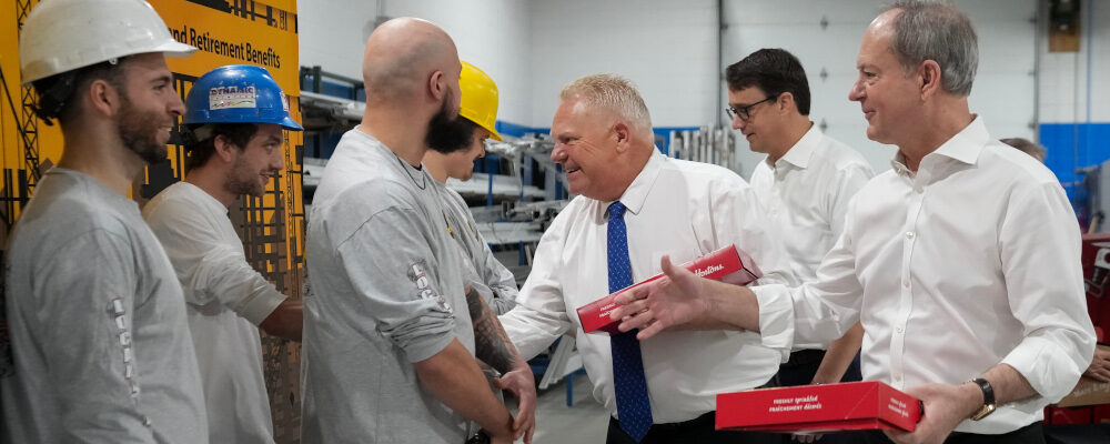 Ontario Premier Doug Ford, centre, and Ontario Finance Minister Peter Bethlenfalvy, right, walk in with doughnuts and greet trades people before painting a mock-up wall during a pre-budget photo opportunity at the International Union of Painters Allied Trades facility in Toronto on Thursday, March 23, 2023. Nathan Denette/The Canadian Press. 