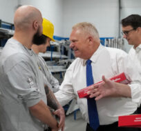 Ontario Premier Doug Ford, centre, and Ontario Finance Minister Peter Bethlenfalvy, right, walk in with doughnuts and greet trades people before painting a mock-up wall during a pre-budget photo opportunity at the International Union of Painters Allied Trades facility in Toronto on Thursday, March 23, 2023. Nathan Denette/The Canadian Press. 