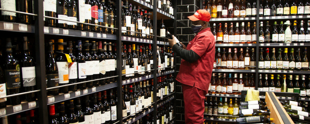 A man stocks shelves with bottles of wine at a Johannesburg liquor store in Johannesburg Monday, Aug. 17, 2020. Denis Farrell/AP Photo.