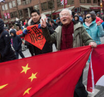 People carry Chinese and Canadian flags while marching in the Chinese New Year Parade in Vancouver on Sunday, Feb. 10, 2019. Darryl Dyck/The Canadian Press. 