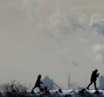 People cross-country ski in the cold weather as an industrial plant is shown in the back ground in Toronto on Friday, Feb. 4, 2022. Nathan Denette/The Canadian Press. 