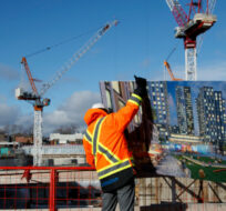 A worker is seen affixing signage for a development prior to a news conference at a construction site that will soon house residential housing in Toronto, Thursday, Jan. 16, 2020. Cole Burston/The Canadian Press. 