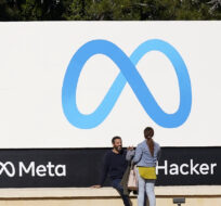 People talk near a Meta sign outside of the company's headquarters in Menlo Park, Calif. on March 7, 2023. Jeff Chiu/AP Photo.