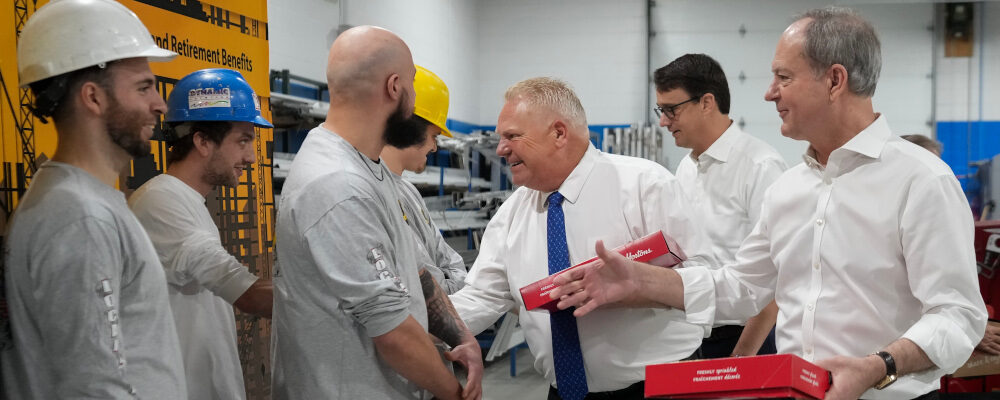 Ontario Premier Doug Ford, centre, and Ontario Finance Minister Peter Bethlenfalvy, right, walk in with doughnuts and greet trades people before painting a mock-up wall during a pre-budget photo opportunity at the International Union of Painters' Allied Trades facility in Toronto on Thursday, March 23, 2023. Nathan Denette/The Canadian Press. 