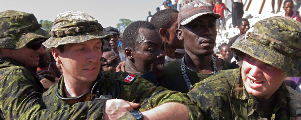 Members of the Royal 22nd Regiments assist United Nations soldiers try to keep food distribution orderly as they perform crowd control at an food aid distribution point in Leogane, Haiti  Friday January 22, 2010. Adrian Wyld/The Canadian Press. 