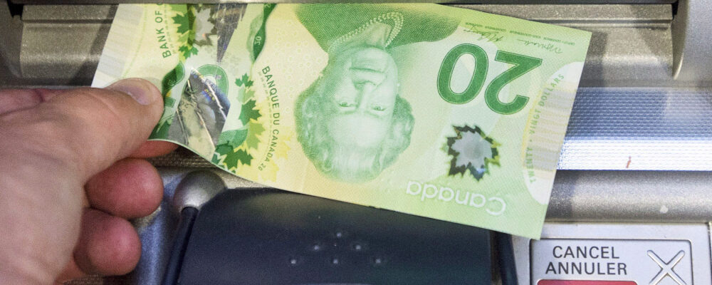 Money is removed from a bank machine in Montreal. Ryan Remiorz/The Canadian Press.