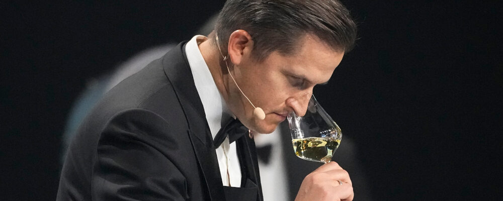 Raimonds Tomsons of Latvia, smells at a glass of white wine during the Best Sommelier of the World in Paris, Sunday, Feb. 12, 2023. Michel Euler/AP Photo.