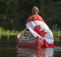 Paddler Gus Vanboxtel from Beaverbrook celebrates Canada Day on the waters of Bass Lake in central Ontario on July 1, 2021. Fred Thornhill/The Canadian Press.