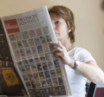 Diane Piacente reads a copy of La Presse in a coffee shop near Montreal. Graham Hughes/The Canadian Press.