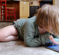 Lizzie Dale sprawls on the floor to play games on an iPad in Lake Oswego, Ore., Oct. 30, 2020. Sara Cline/AP Photo. 