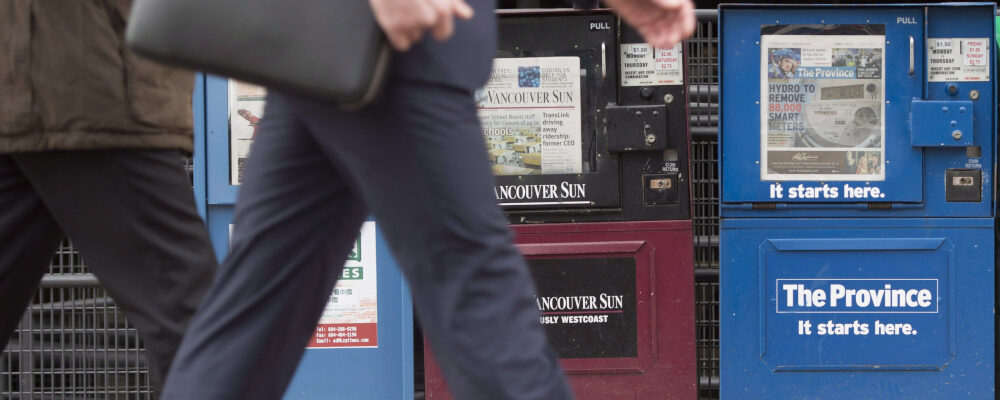 A man walks past newspaper boxes containing the Vancouver Sun and the Province in downtown Vancouver. Jonathan Hayward/The Canadian Press.