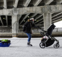 A skater pushes a baby stroller while pulling a sled along the Rideau Canal Skateway on March 5, 2022. Justin Tang/The Canadian Press.