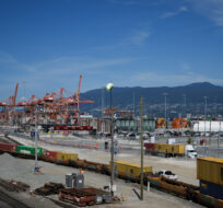 A transport truck carries cargo containers from the Centerm Container Terminal at port as others arrive by train in Vancouver on July 14, 2023. Darryl Dyck/The Canadian Press.