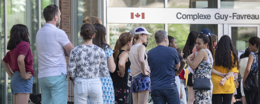 People line up outside the Guy Favreau federal building while waiting to apply for a passport in Montreal on June 26, 2022. Graham Hughes/The Canadian Press.