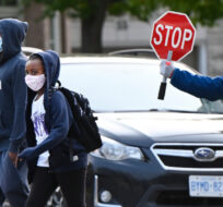 Children cross the street while arriving at Portage Trail Community School which is part of the Toronto District School Board (TDSB) in Toronto on Tuesday, September 15, 2020. Nathan Denette/The Canadian Press. 