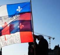 Protesters embrace while holding Canadian and Quebec flags in Ottawa, Friday, April 29, 2022. Sean Kilpatrick/The Canadian Press. 