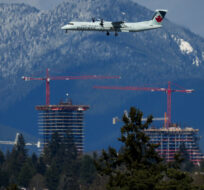 An Air Canada Express aircraft travels past construction cranes at the Oakridge Centre mall redevelopment in Vancouver on April 11, 2023. Darryl Dyck/The Canadian Press.