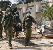 Israeli soldiers carry bodies of killed Israelis in kibbutz Kfar Azza on Tuesday, Oct. 10, 2023. Ohad Zwigenberg/AP Photo.