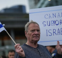 A man holds an Israeli flag and a sign during a vigil organized by the Jewish Federation of Greater Vancouver in support of those killed in Israel during a terrorist attack by Hamas. Darryl Dyck/The Canadian Press.