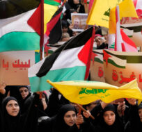 Hezbollah supporters wave Lebanese, Palestinian and their group flags, as they hold Arabic placards that read:"At your service Gaza," during a protest in Beirut, Lebanon, Friday, Oct. 13, 2023. Hussein Malla/AP Photo. 
