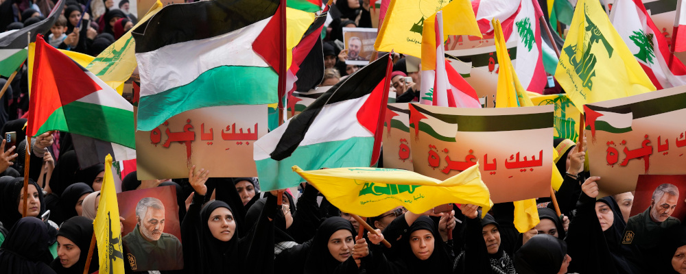 Hezbollah supporters wave Lebanese, Palestinian and their group flags, as they hold Arabic placards that read:"At your service Gaza," during a protest in Beirut, Lebanon, Friday, Oct. 13, 2023. Hussein Malla/AP Photo. 