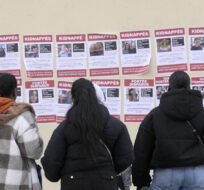 People watch posters pasted by the Union of Jewish French Students on Oct. 16, 2023 in Paris. Michel Euler/AP Photo.