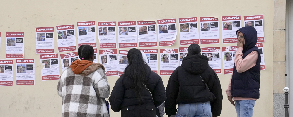 People watch posters pasted by the Union of Jewish French Students on Oct. 16, 2023 in Paris. Michel Euler/AP Photo.
