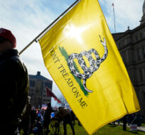 A demonstrator carries a Don't Tread On Me flag during a rally at the Capitol building in Lansing, Mich., Saturday, Nov. 14, 2020. Paul Sancya/AP Photo. 