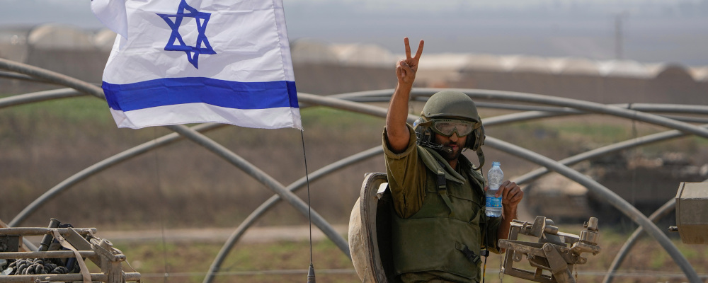 An Israeli soldier flashes a V-sign from an armoured personnel carrier as they head towards the Gaza Strip border in southern Israel, Saturday, Oct. 14, 2023. Ariel Schalit/AP Photo. 