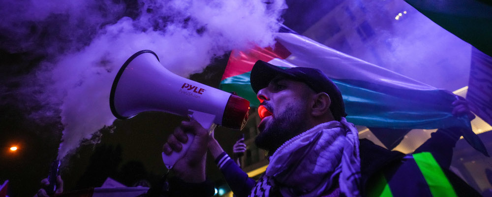 A man uses a bullhorn as smoke bombs are set off during a demonstration in support of Palestine, in Vancouver, on Thursday, October 19, 2023. Darryl Dyck/The Canadian Press. 