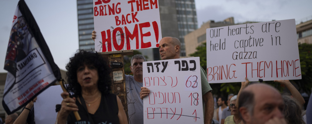 Residents of Kibbutz Kfar Azza wave signs during a demonstration in solidarity with friends and relatives held hostage in the Gaza Strip, in Tel Aviv, Israel on Nov. 2, 2023. Oded Balilty/AP Photo.