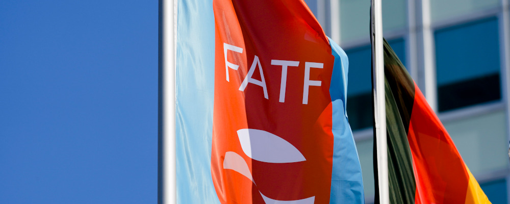 A flag with the logo of the Financial Action Task Force, FATF, waves in the wind next to the German national flag during a meeting of the task force at the Congress Center in Berlin, Germany, Friday, June 17, 2022. Markus Schreiber/AP Photo. 
