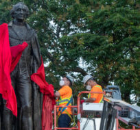 City workers remove the red sheet before the removal of the statue of Sir John A. Macdonald in Kingston, Ontario on Friday June 18, 2021.  Lars Hagberg/The Canadian Press. 