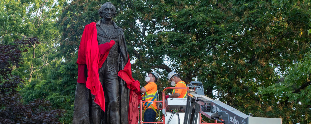 City workers remove the red sheet before the removal of the statue of Sir John A. Macdonald in Kingston, Ontario on Friday June 18, 2021.  Lars Hagberg/The Canadian Press. 